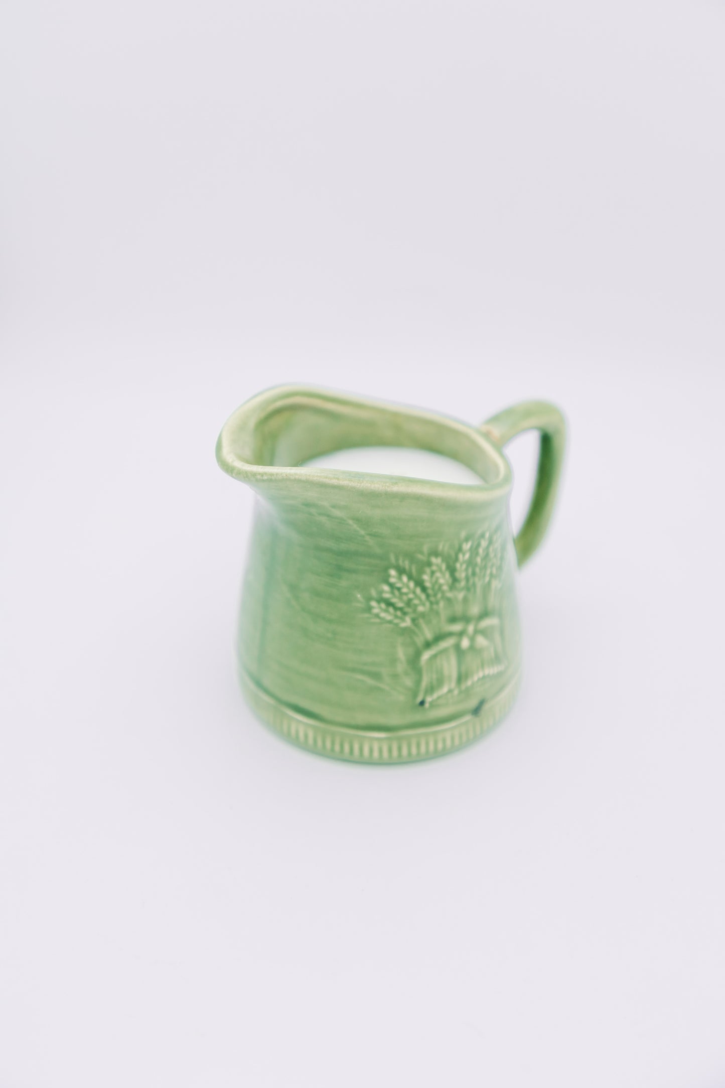 green ceramic creamer with floral design